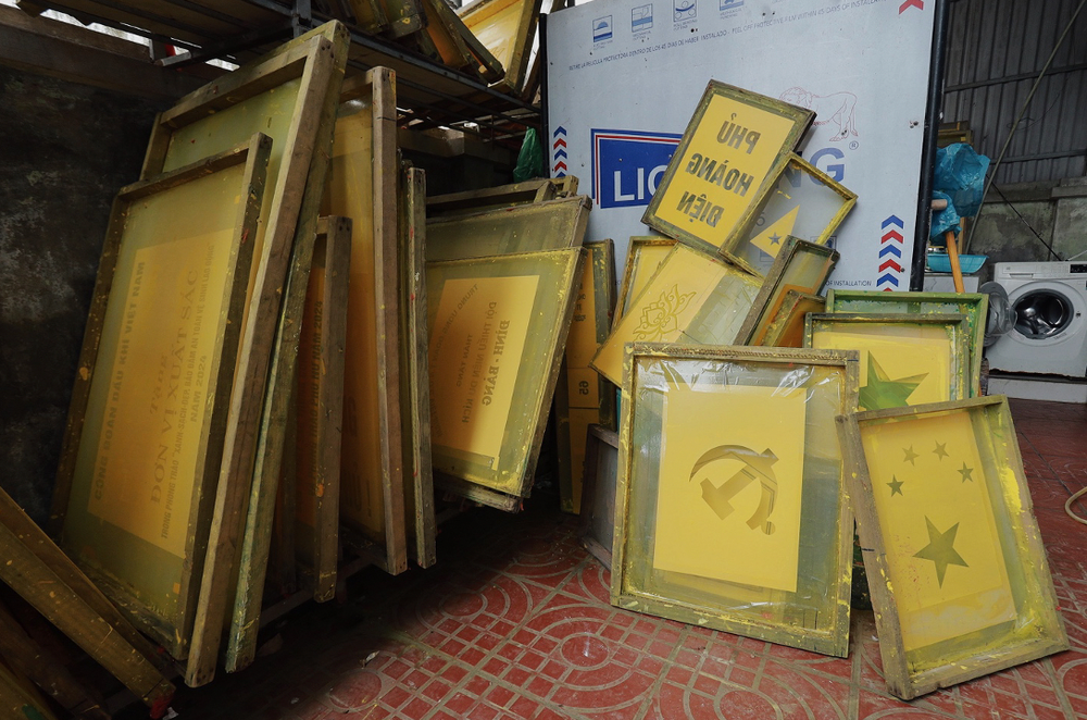 Những khung in được cất gọn một góc. Ngoài in quốc kì, cô Nhung còn in các loại cờ khác như cờ chúc mừng, cờ chứng nhận, … anh-chup-man-hinh-2025-04-28-luc-134709.png