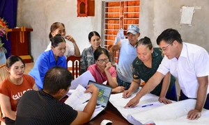 Cán bộ Trung tâm Phát triển quỹ đất huyện Kim Bôi trao đổi với người dân về phương án bồi thường, đền bù giải phóng mặt bằng.