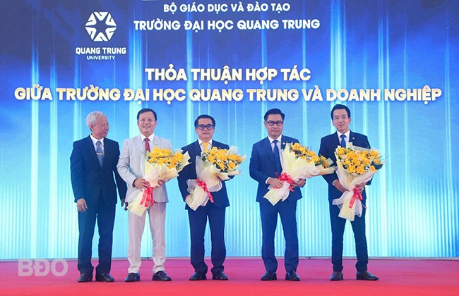 Trường ĐH Quang Trung trao, nhận biên bản ghi nhớ và tặng hoa chúc mừng các DN, đối tác. Ảnh: HỒ ĐIỂM viewimageaspx-2.jpg
