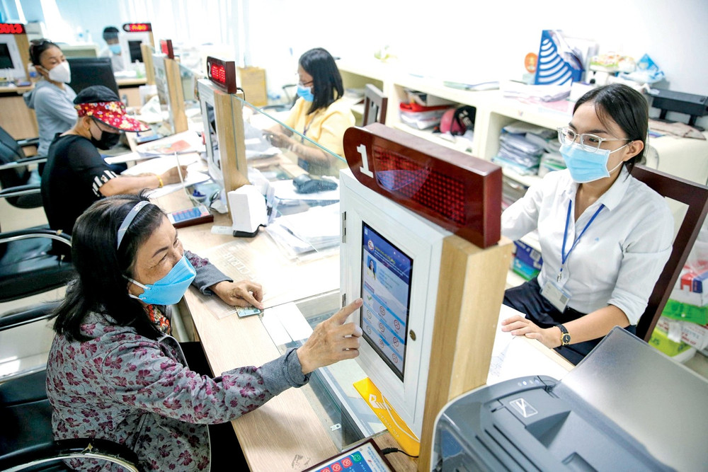 Người dân sử dụng máy tính bảng hoặc thiết bị điện tử để đánh giá chất lượng phục vụ của cán bộ tại quầy giao dịch. Nguồn: Baochinhphu.vn bai1.jpg