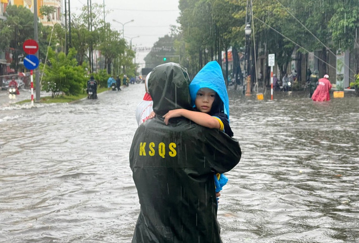 Một chiến sĩ thuộc Bộ Chỉ huy quân sự tỉnh Kiên Giang hỗ trợ em bé khi xe người thân không thể di chuyển. (Ảnh: Phương Vũ). Nhiều tuyến đường thành phố biển Rạch Giá chìm sâu trong biển nước