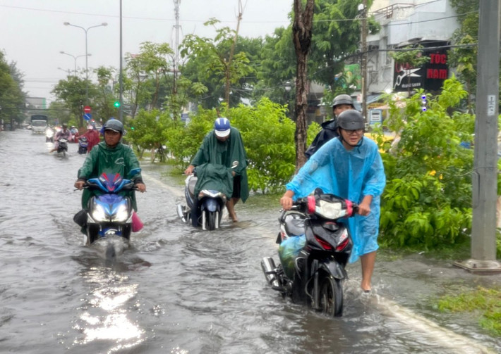 Do trời mưa đúng giờ đi làm của người dân nên việc đi lại gặp nhiều khó khăn. (Ảnh: Phương Vũ). Nhiều tuyến đường thành phố biển Rạch Giá chìm sâu trong biển nước