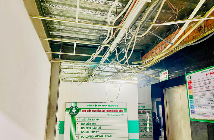 Hệ thống dây điện treo lủng lẳng trên trần nhà tầng 1 nơi hàng lang đón tiếp người khám bệnh chuyên khoa Bệnh viện đa khoa Medic - Bình Dương vừa khám chữa bệnh vừa thi công xây dựng hệ thống PCCC
