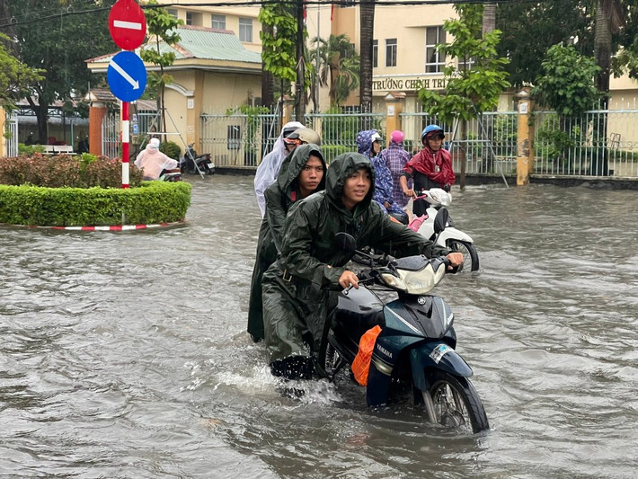 Bộ Chỉ huy quân sự tỉnh Kiên Giang nhanh chóng cử 20 cán bộ, chiến sĩ hỗ trợ người dân vượt qua những chỗ nước sâu an toàn. (Ảnh: Phương Vũ). Nhiều tuyến đường thành phố biển Rạch Giá chìm sâu trong biển nước