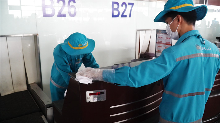 Nhân viên vệ sinh khử khuẩn quầy check-in trước khi đón khách Nhân viên vệ sinh khử khuẩn quầy check-in trước khi đón khách