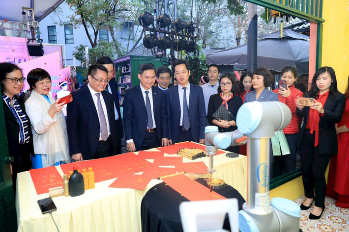Các đại biểu trải nghiệm màn trình diễn robot viết thư pháp. Ảnh: H.Hải sach-2.jpg